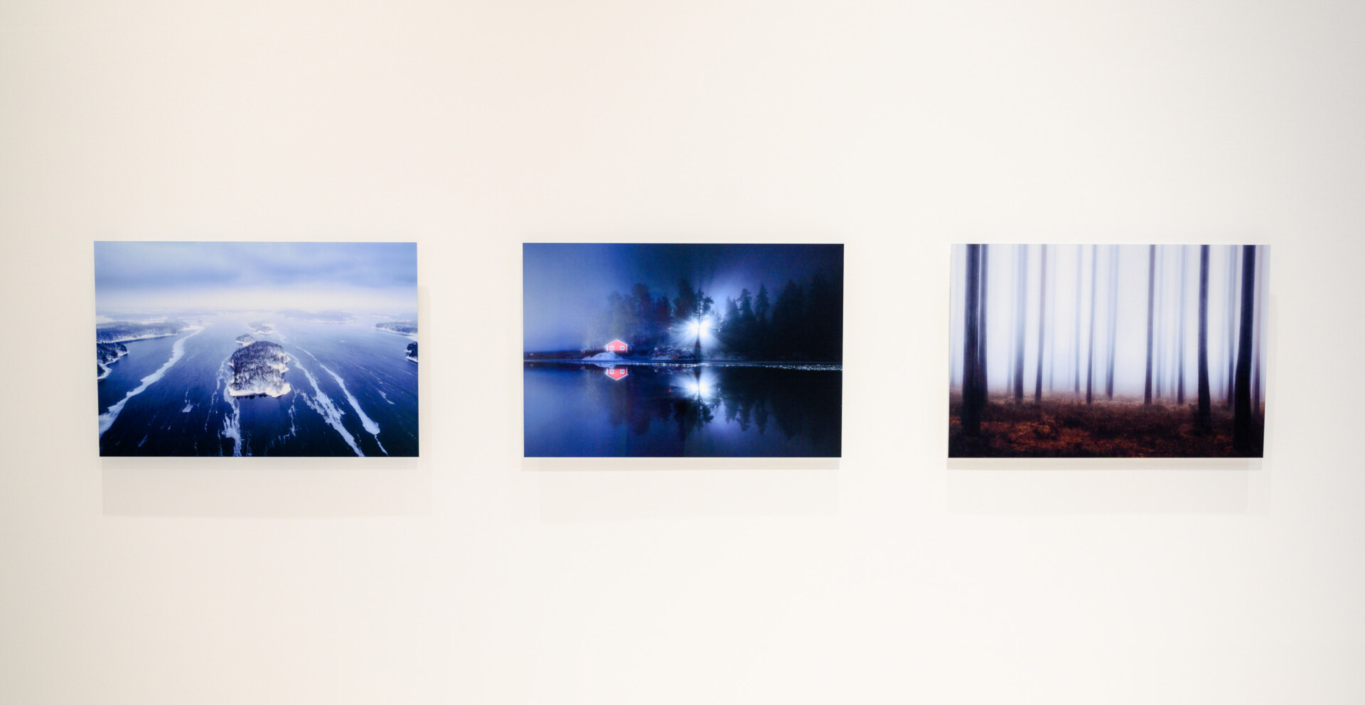 Three photos on a white wall. The photos show views from Barösund in Ingå.